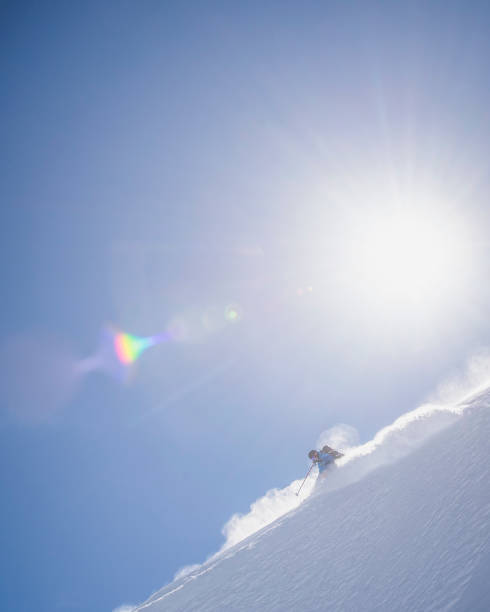 backcountry-skifahrer steigt verschneiten bergrücken ab - telemark skiing stock-fotos und bilder