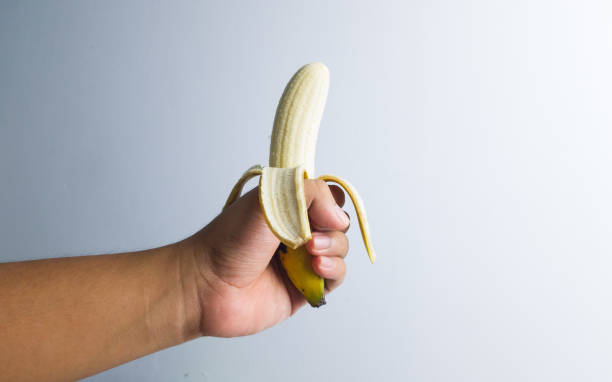 istock asian man hand holding peeled banana with white backgound 1327366372