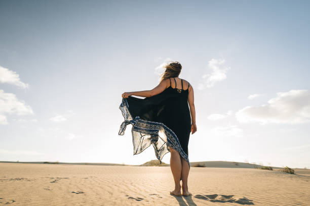 istock Young woman dances on sand dune 1327366413