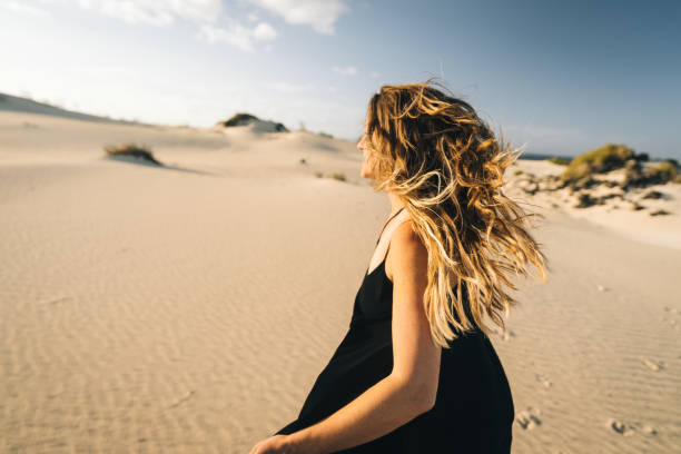 istock Young woman runs barefoot through sand dunes 1327366414