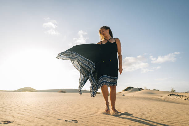 istock Young woman dances on sand dune 1327366421