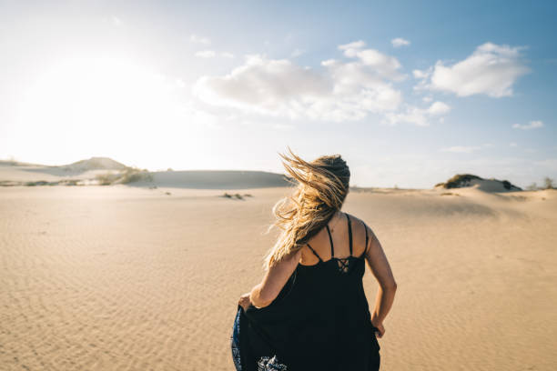 istock Young woman runs barefoot through sand dunes 1327366952