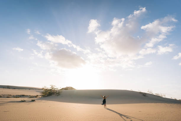 istock Young woman dances on sand dune 1327366970