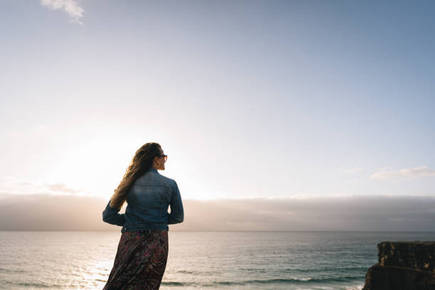 istock Young woman relaxes on coastal cliffs at sunrise 1327367225