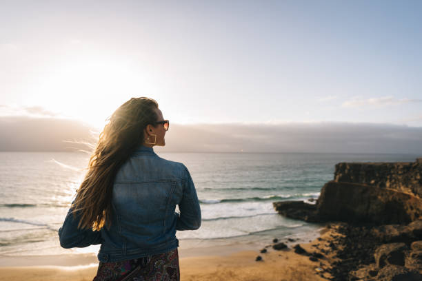 istock Young woman relaxes on coastal cliffs at sunrise 1327367242