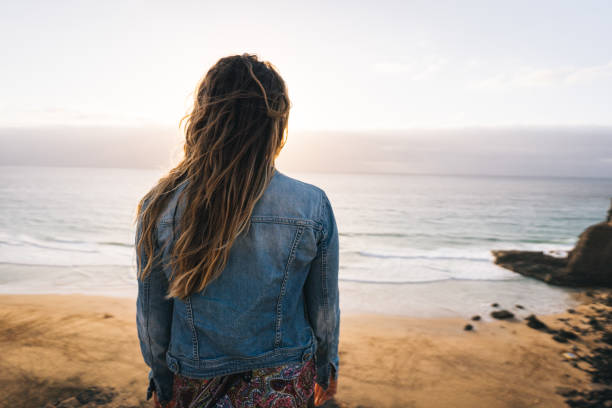 istock Young woman relaxes on coastal cliffs at sunrise 1327367378