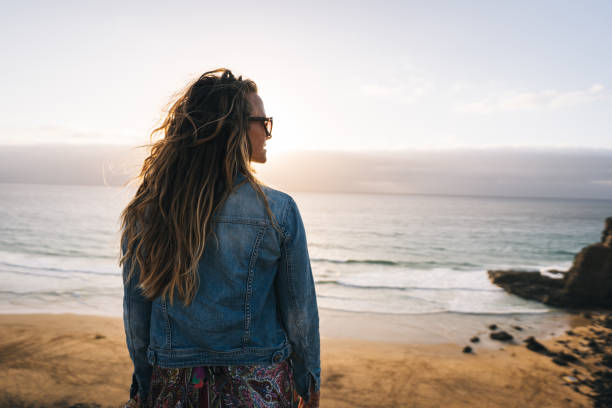 istock Young woman walks along coastal cliffs at sunrise 1327367925