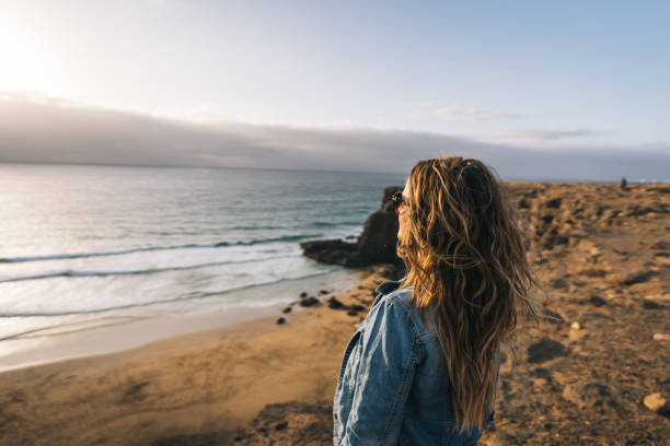 istock Young woman relaxes on coastal cliffs at sunrise 1327367955