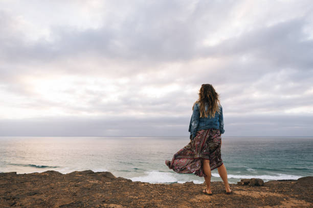 istock Young woman relaxes on windy coastal cliffs 1327368114
