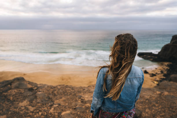 istock Young woman relaxes on windy coastal cliffs 1327368153