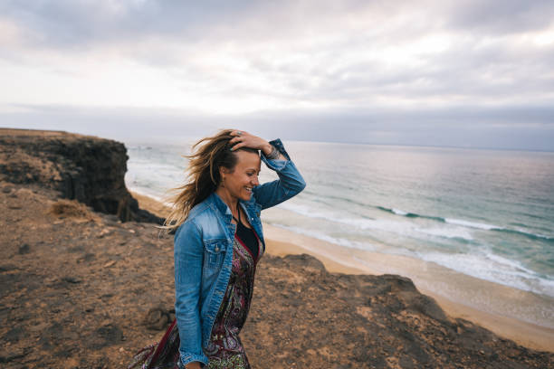 istock Young woman walks along coastal cliffs at sunrise 1327368175