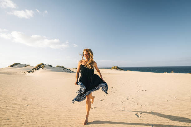 mujer joven corre a lo largo de la duna de arena costera en lanzarote, islas canarias - isla de lanzarote fotografías e imágenes de stock