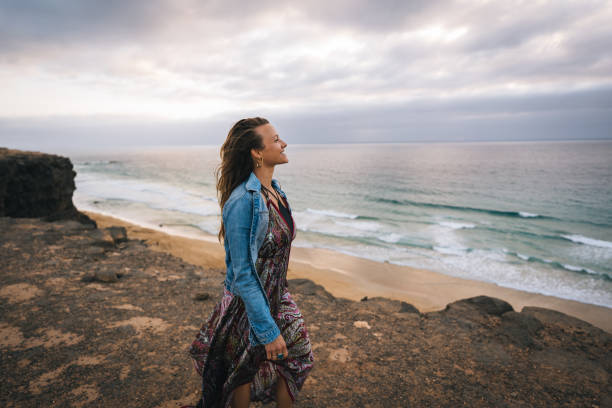 istock Young woman walks along windy coastal cliffs 1327368832