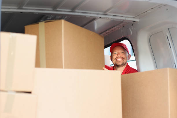 istock Smiling male courier pulls out cardboard box from car 1327370574
