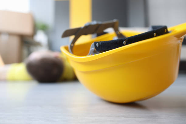 Yellow worker helmet on floor beside motionless construction worker. Accident during construction and renovation concept