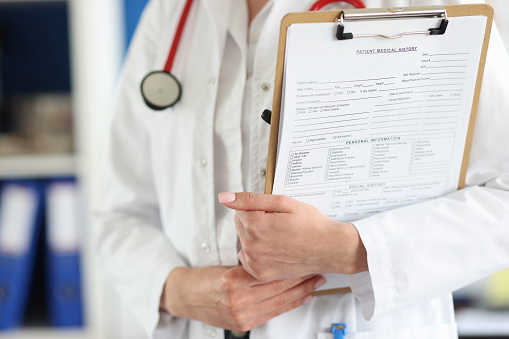 Doctor holds clipboard with the patient medical history. Medical services and patient examination concept