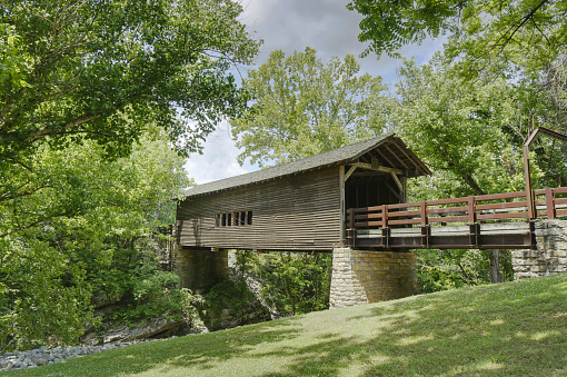 Harrisburg covered bridge in Tennessee in the summer surrounded by green trees and grass.