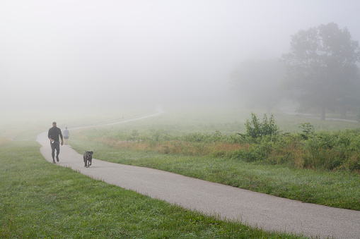 King of Prussia, USA - July 4, 2021. A man walking dog on trail at Valley Forge National Historic Park, Pennsylvania, USA