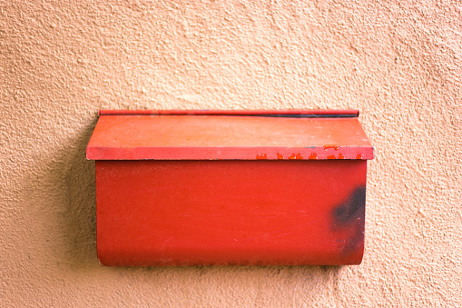 Santa Fe Style: Old Orange Mailbox on Adobe Wall. Copy space available.