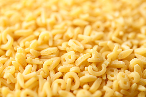 High angle view of stacked alphabet soup pasta texture background with shallow depth of field.