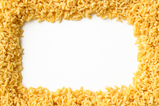 Overhead shot of stacked alphabet soup pasta frame on white background.
