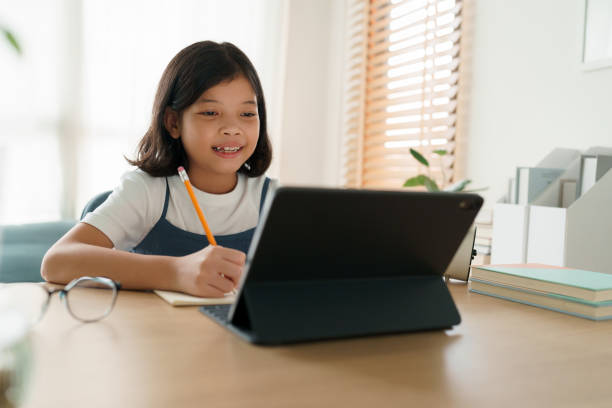 istock Asian little girl using tablet digital and do homework 1327389796