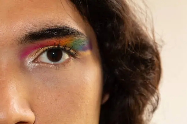 close up of eyes made up with a rainbow on a white background