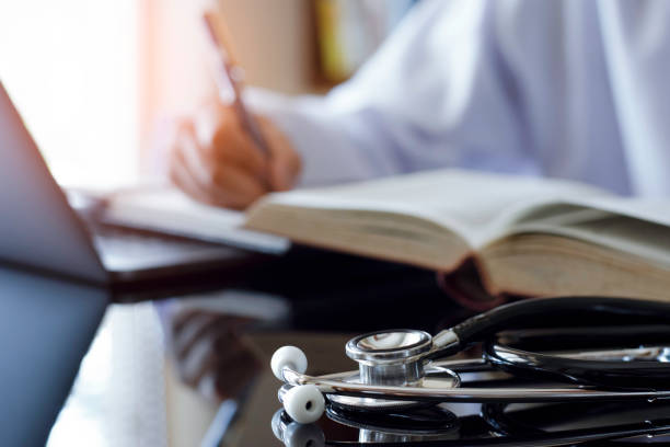 istock Doctor or physician read text book , work on laptop computer 1327394001