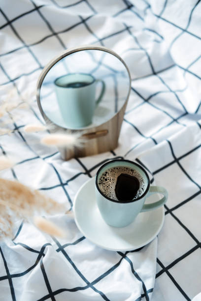 Morning cozy mood. Coffee in the bed. A cup of black coffee in bed on white checkered blanket
