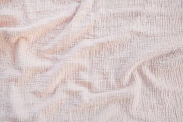 Photo of Muslin cloth texture background in neutral tones. Muslin cotton fabric of plain weave. Muslin is a soft, woven, 100-percent cotton multi-layer cloth popular for baby cloths and blankets