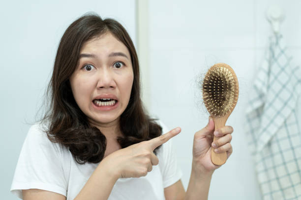 istock Asian young woman concerned about hair fall problem. 1327397620