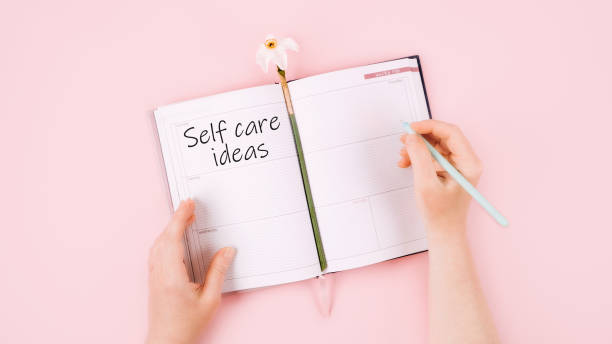 istock Self Care ideas, wellbeing routine, self-care activities concept with open notebook, flower narcissus and female hand on pink background 1327397638