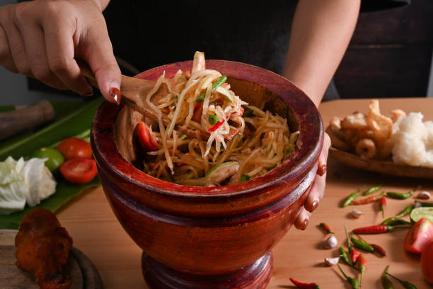 Close up woman holding"nmortar with spicy papaya salad. Close up woman holding"nmortar with spicy papaya salad. tam o'shanter stock pictures, royalty-free photos & images