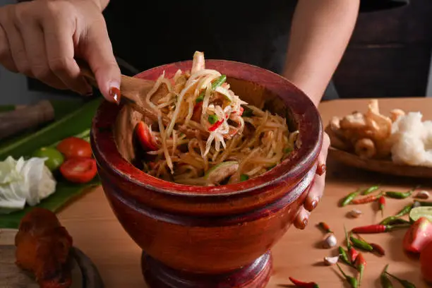 Close up woman holding"nmortar with spicy papaya salad.