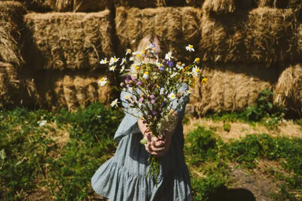 Cottagecore, Countryside aesthetics, Farming, Farmcore, Countrycore, slow life. Young girl in peasant dress and with flowers enjoying nature on country farm. Modern rural fantasy, pastoral aesthetic.