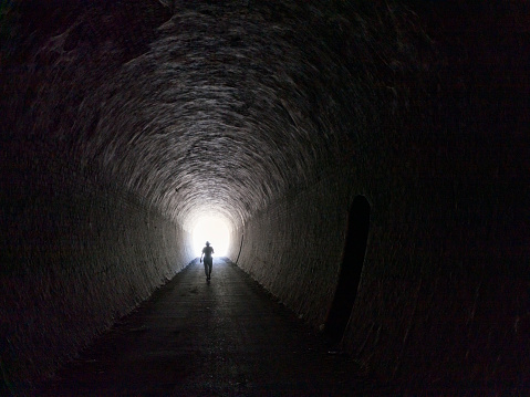 A woman walks towards the light at the end of the tunnel. Copy space. Concept image.