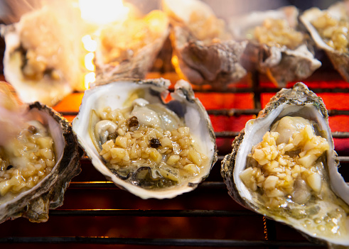 Fresh oysters grilled with condiments on the stove.Thai-Chinese style seafood.