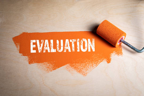 istock EVALUATION. Paint roller with orange color on a wooden background 1327404618