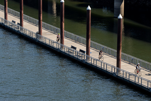 Portland, OR, USA - July 4, 2021: A small group of senior women cyclists are seen riding on Eastbank Esplanade along the east shore of the Willamette River in Portland, Oregon, on Sunday, 4th of July.