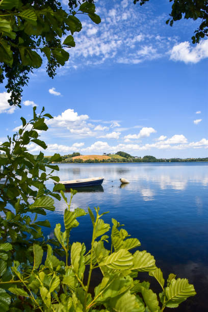 Beautiful view on a Biale Lake (Kaszuby lake district) seen through the tree. Small boat floating on a clean water surface.