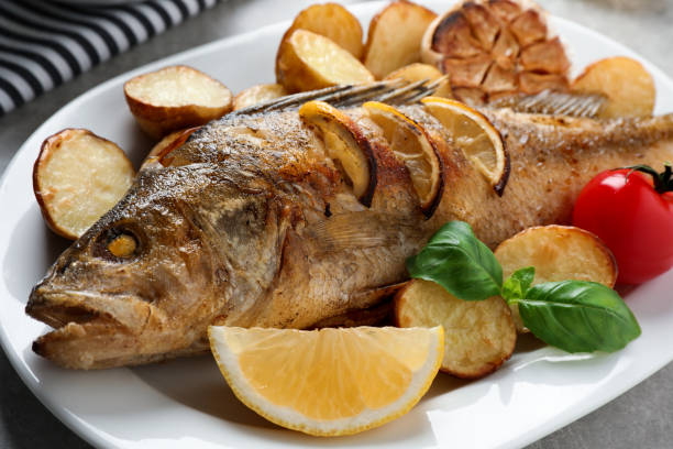 istock Tasty homemade roasted perch with garnish on table, closeup. River fish 1327417893
