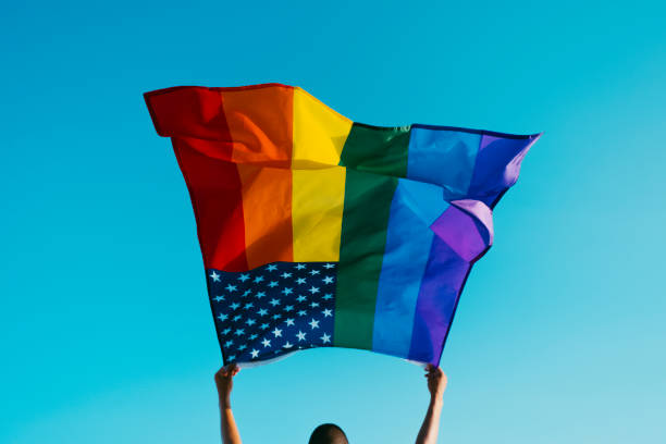 istock young man waves a rainbow US flag on the sky 1327419619