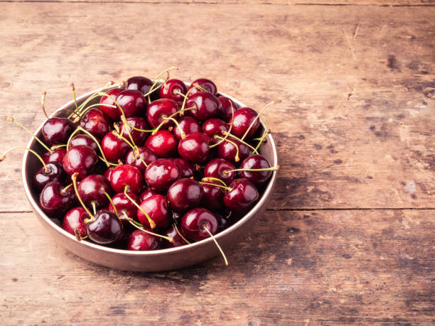 istock Bowl with ripe cherries on a wooden table, top view, copy space 1327419938