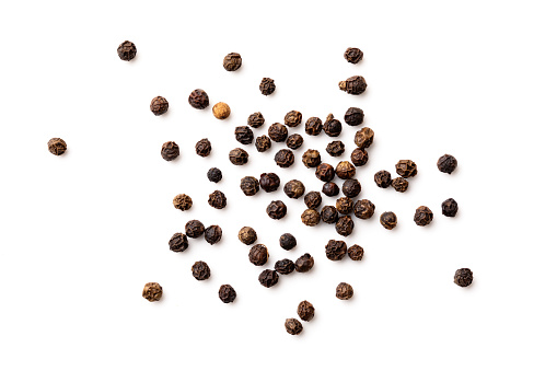 Spicy red chillies in an old metal measuring container on a black background.