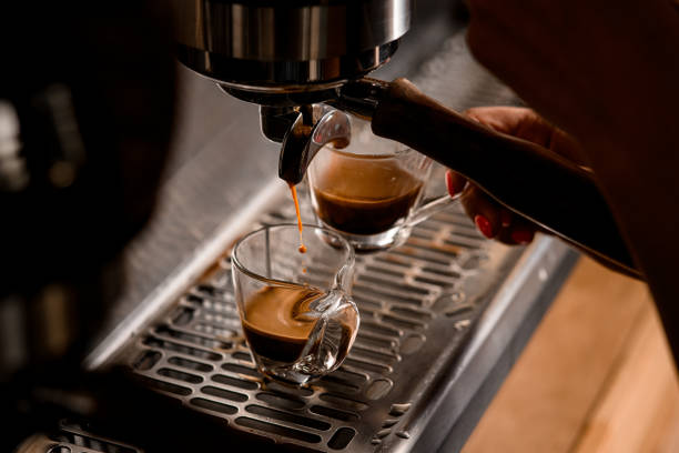 primo piano di flusso di caffè caldo che scorre da una macchina per caffè espresso in tazza - pouring coffee human hand cup foto e immagini stock