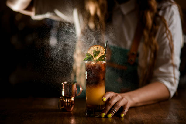 Close-up of glass with coffee cocktail and female bartender gently sprinkles on it stock photo