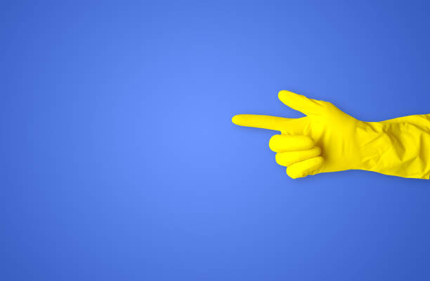 istock Hand in a yellow rubber glove points to the side on a blue background 1327422356