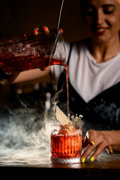 istock woman bartender accurate pours cold beverage from mixing cup into steaming glass 1327423532