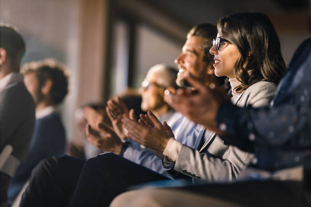 felice imprenditrice e i suoi colleghi che applaudono in un evento educativo in sala riunioni. - riunione foto e immagini stock