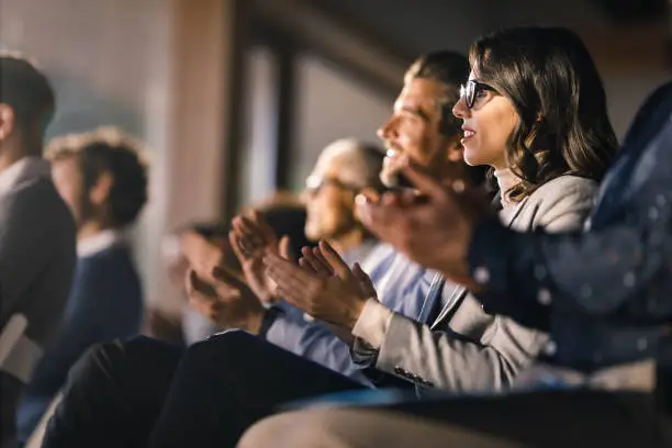 Photo of Happy businesswoman and her colleagues applauding on an education event in board room.